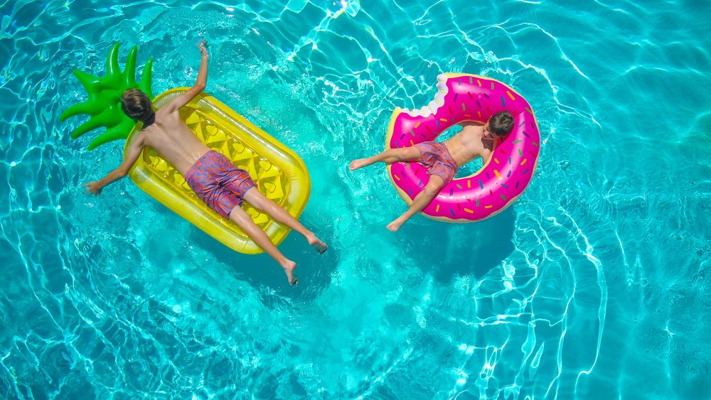 Dos niños con flotador en la superficie de una piscina