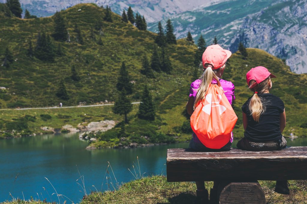 Dos niñas de espaldas con mochila observando un paisaje natural