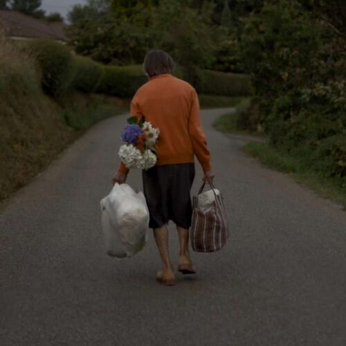 Una mujer de espaldas caminado con una carretera. Fotograma de la película Gregoria