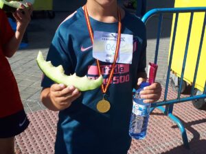 niño con un melón mordido en la mano y una botella de agua en otra mano, uno de los participantes de la carrera infantil melonera