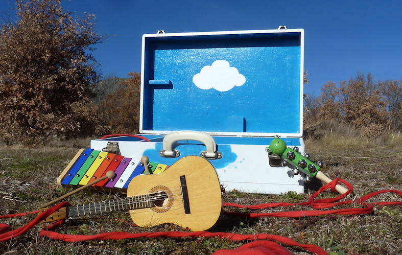 Una caja abierta con instrumentos musicales esparcidos como una guitarra en un bosque