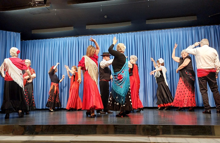 Mujeres de los centros de mayores bailando sevillanas vestidas de faralaes