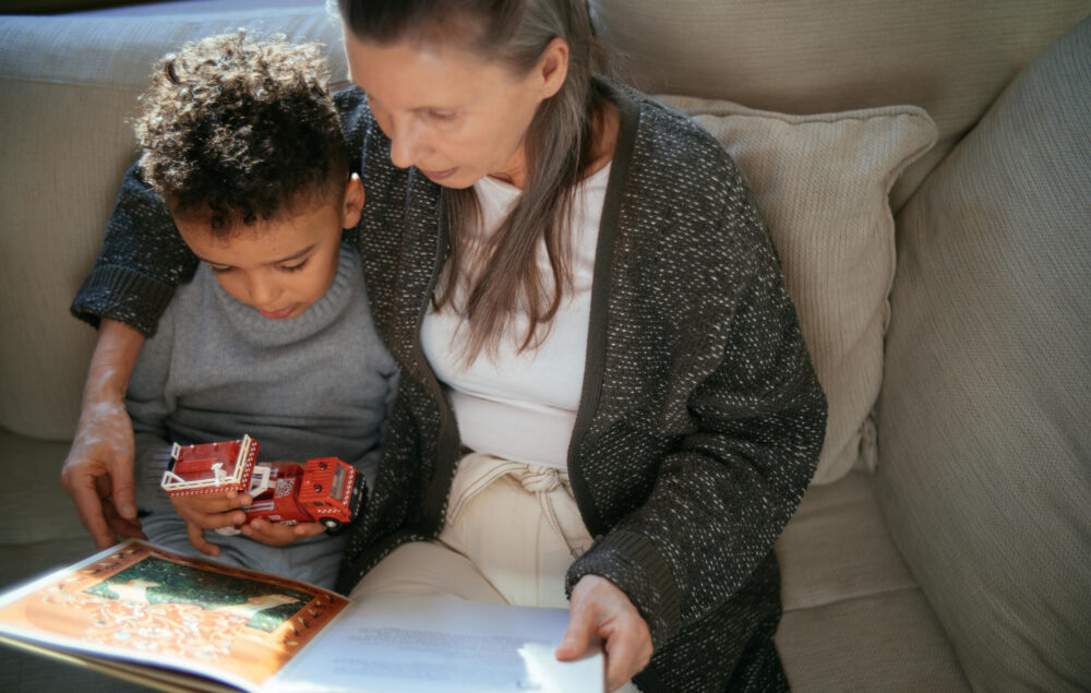 Una abuela leyendo a su nieto en un sofa con un cuento en las manos
