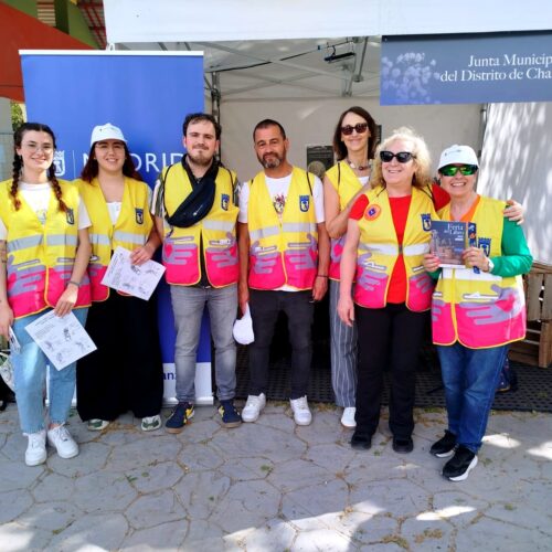 Voluntarios por Madrid con chalecos frente a la caseta de la feria del libro