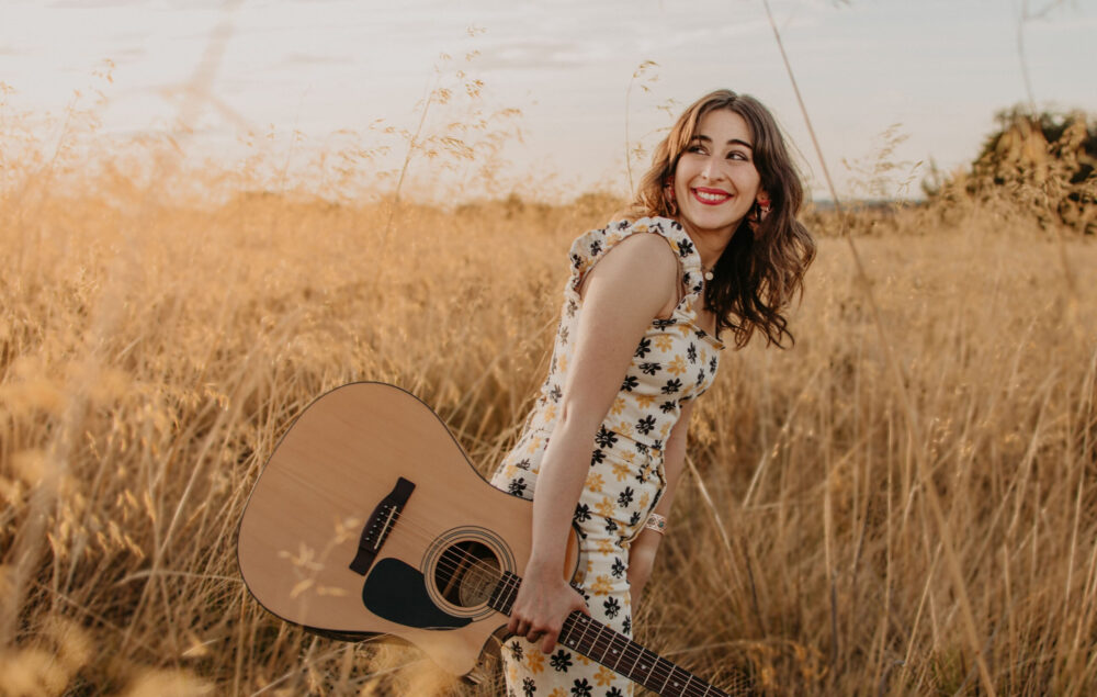 Una mujer con una guitarra y un vestido en un campo de trigo