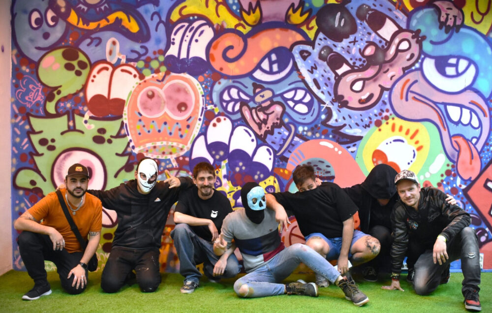 Unos chicos posando frente a una pared grafiteada