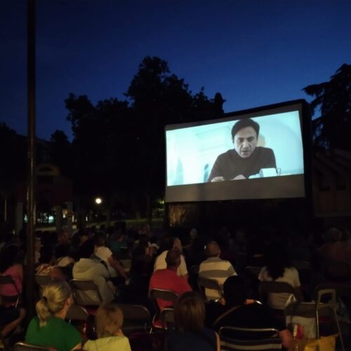 Imagen del cine de verano de Chamartín con el público de espaldas y una película en la pantalla