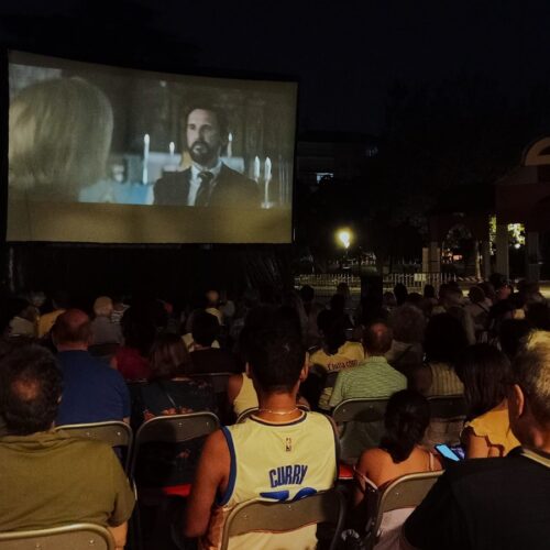 Imagen del cine de verano de Chamartín con el público de espaldas y una película en la pantalla