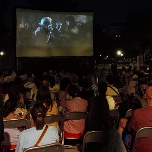 Imagen del cine de verano de Chamartín con el público de espaldas y una película en la pantalla