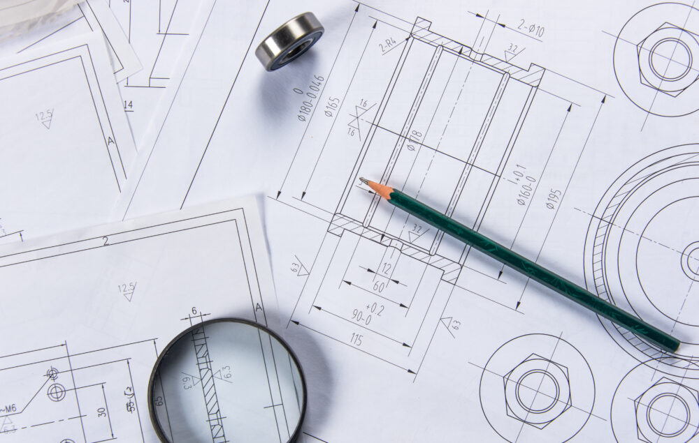 Planos de ingeniería con un lápiz verde encima