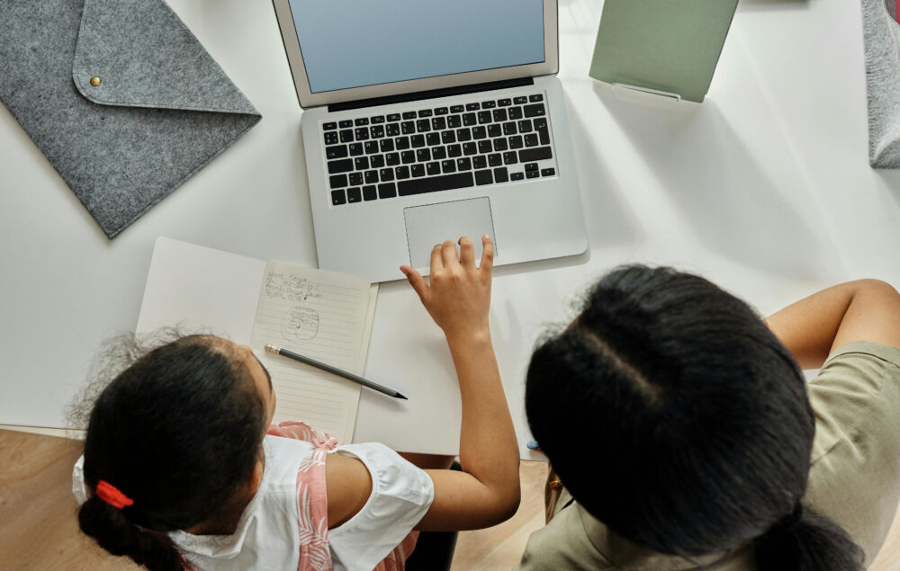 Una mujer enseñando a una niña a usar el ordenador