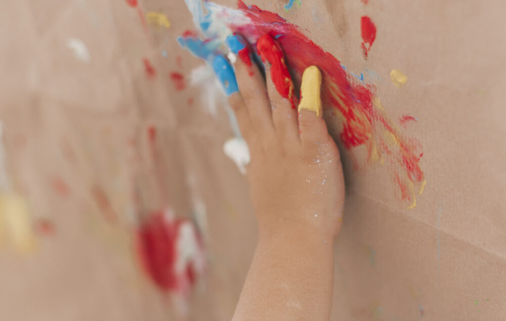 una mano de un niño pintando en una pared