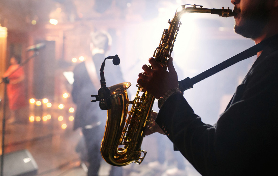 Un saxofonista actuando junto a su banda iluminado por un foco