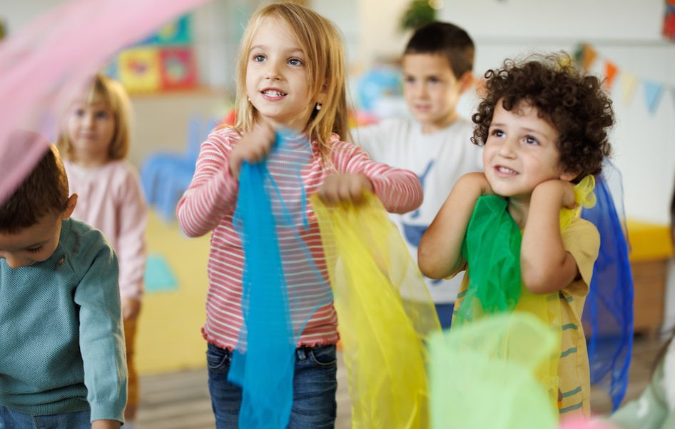 Niños jugando con telas de colores