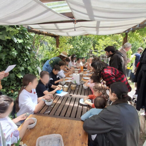 Unas personas, entre ellas, niños y niñas, trabajando en un taller en un huerto urbano