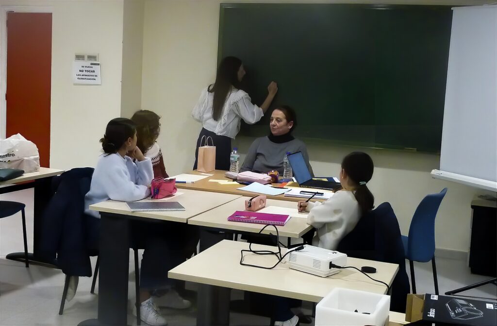 Una niña escribe en una pizarra mientras el resto atienden en un aula