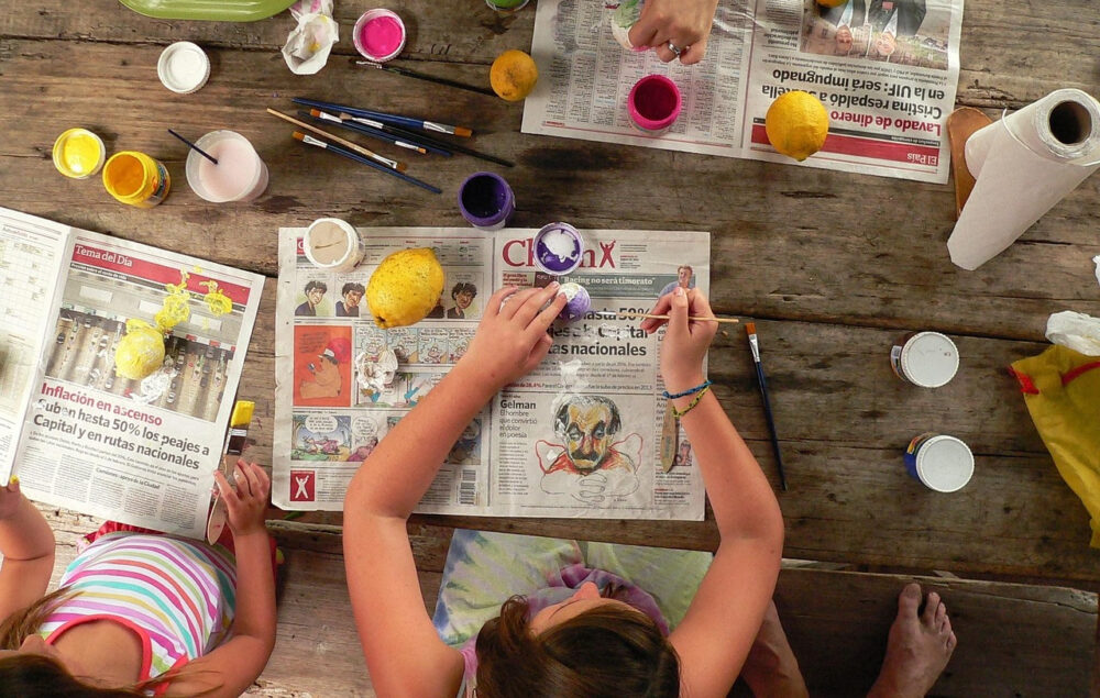 Taller creativo infantil de pintura sobre papel de periódico con colores y pinceles en una mesa de madera, actividad cultural para familias este fin de semana en Chamberí, Madrid