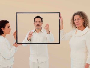 tres personas, en las que dos de ellas son dos mujeres que sujetan un marco en el que se ve a un hombre