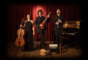 tres músicos de pie sobre un escenario con instrumentos en sus manos