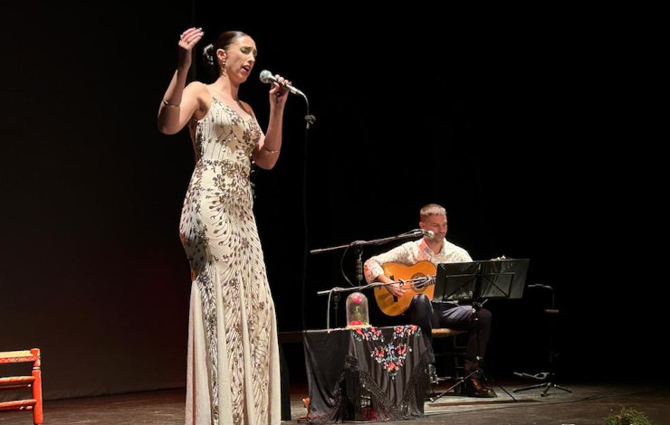 una mujer cantando sobre un escenario junto a un guitarrista
