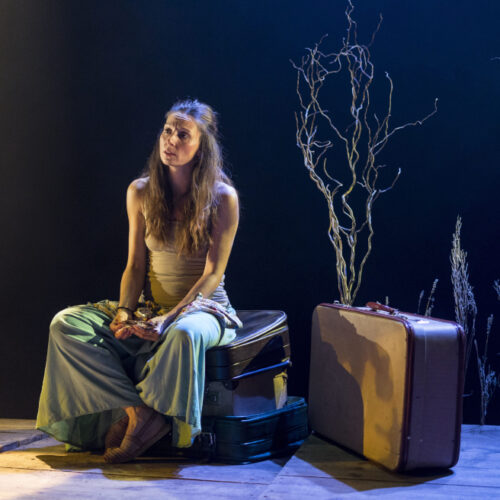 una mujer sentada pensativa con una maleta al lado