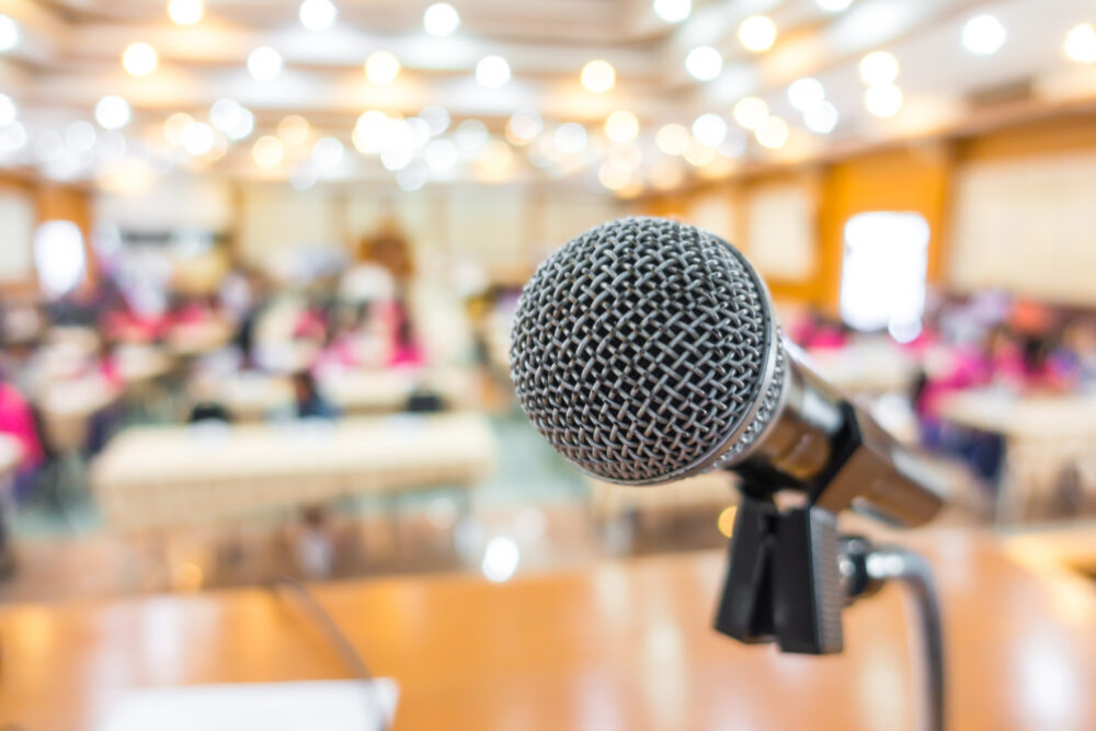 Micrófono en primer plano en una sala con público de una conferencia