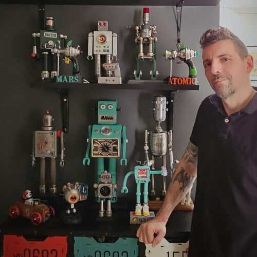 Foto de Juan Andrés Guardia y su exposición 'Robots retrofuturistas' donde aparece el autor con varias de sus obras