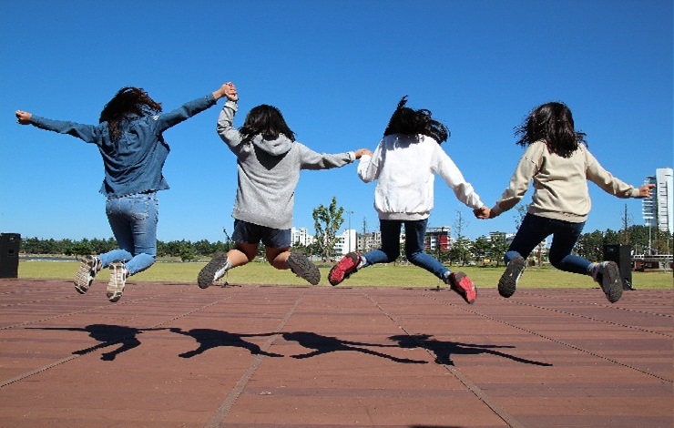 Niños saltando, cogidos de la mano, en una pista deportiva