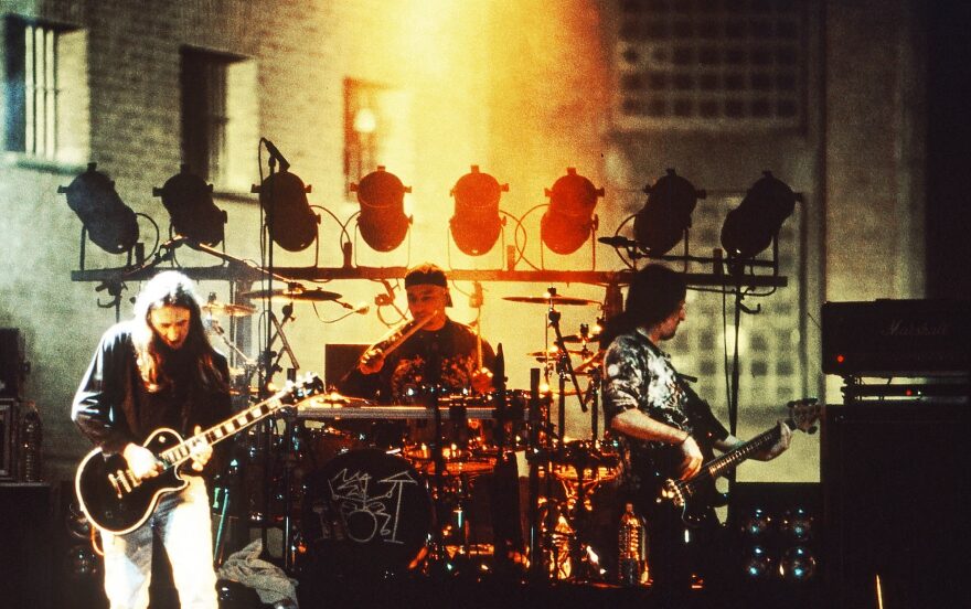 Rosendo y su banda en un concierto sobre un escenario con fondo de colores