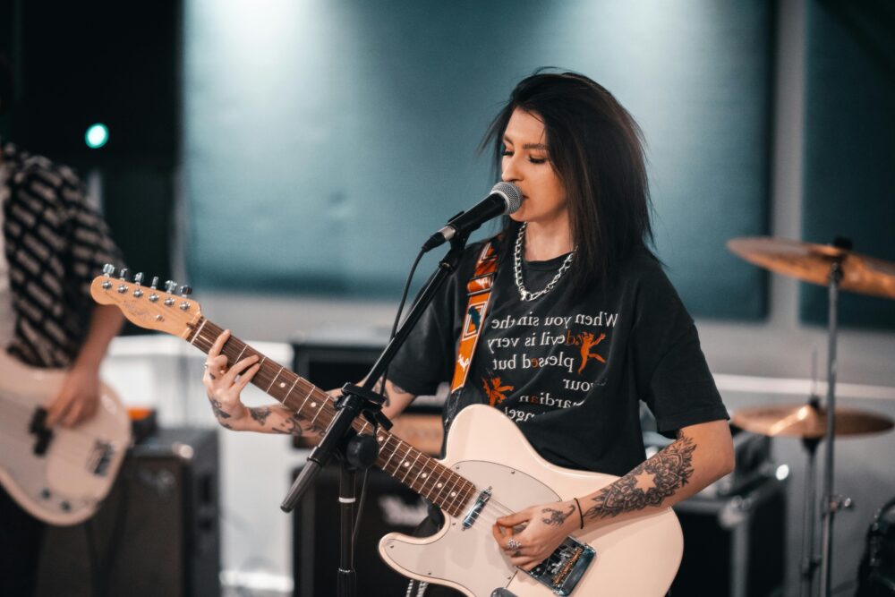 Cantante mujer joven con camiseta negra y guitarra eléctrica