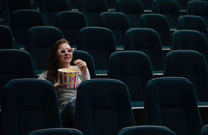 Una mujer comiendo palomitas en una sala de cine