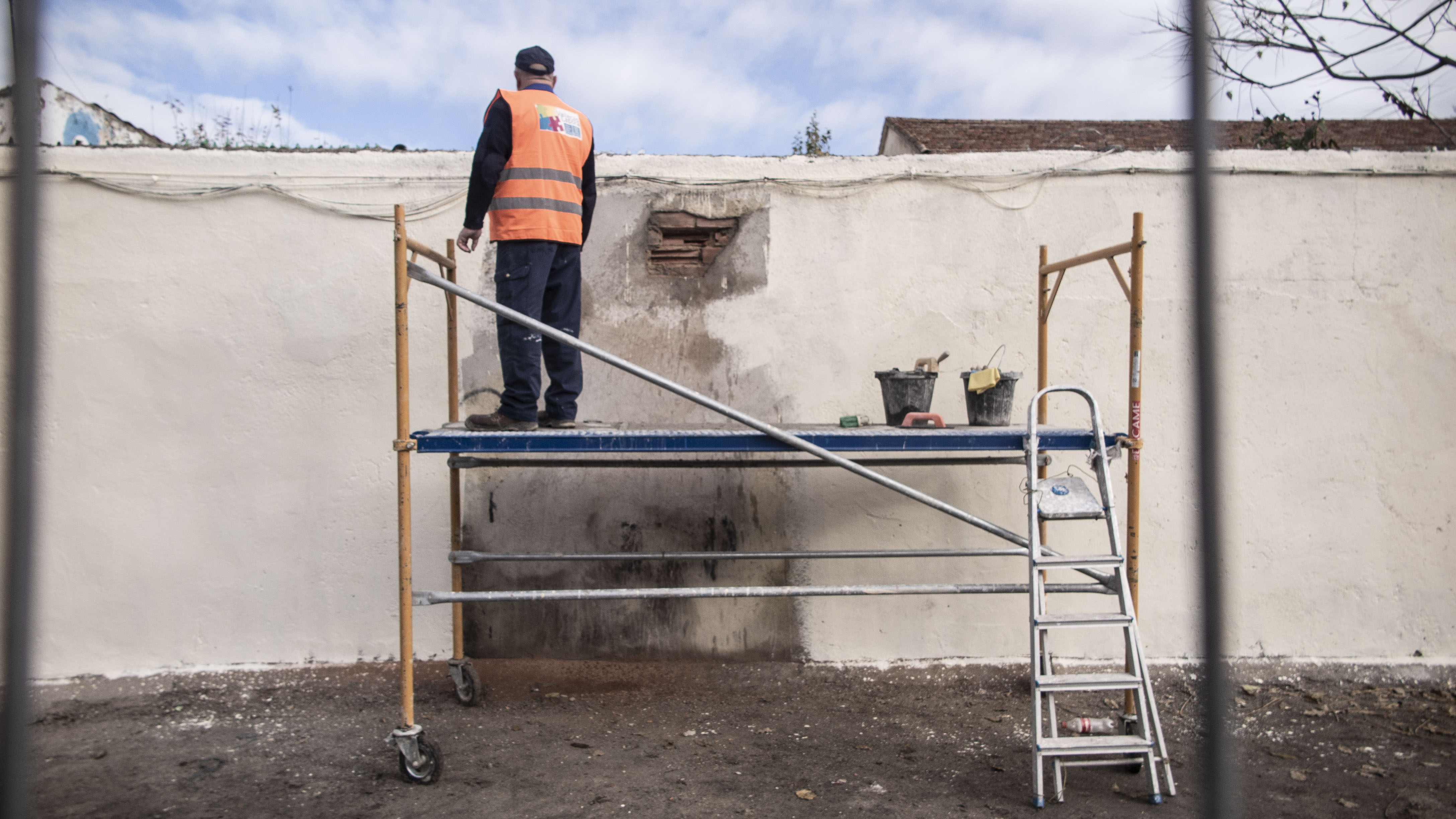 Los miembros de Vallecas Labora reparan la pared en la que se instalará el mural conmemorativo