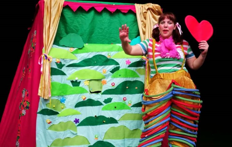 Sobre el escenario, un teatro de guiñol y una actriz con un traje de clown narrando la historia de rita la gotita