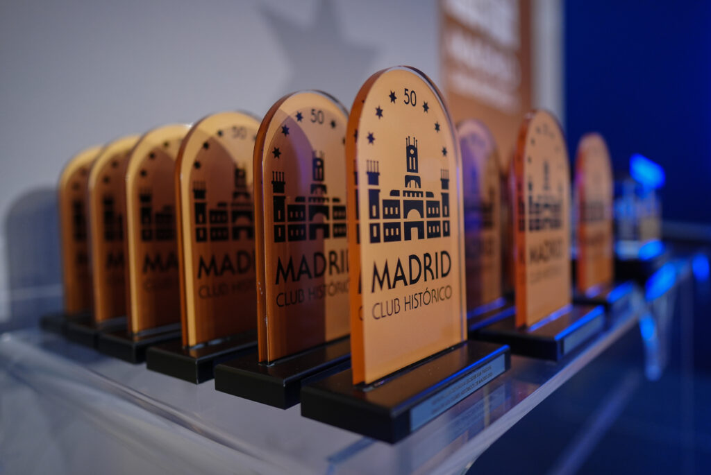 Primer plano de los trofeos, metopas de color amarillo con la ilustración del Palacio de Cibeles