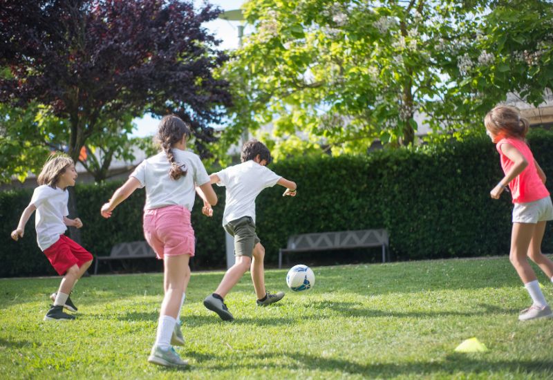 niños jugando al fútbol sobre césped