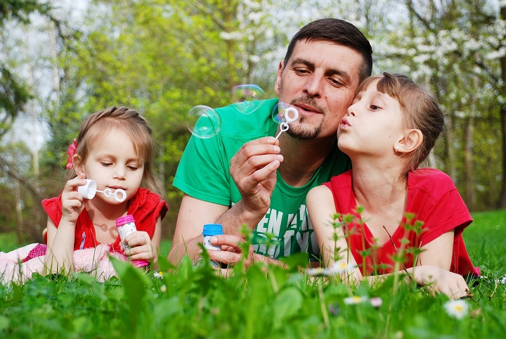 Padre y niñas haciendo burbujas de jabón