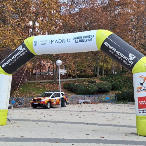 Salida del Cross escolar de Tetuán 2025 donde se ve el coche de seguridad de fondo y el arco con organizadores