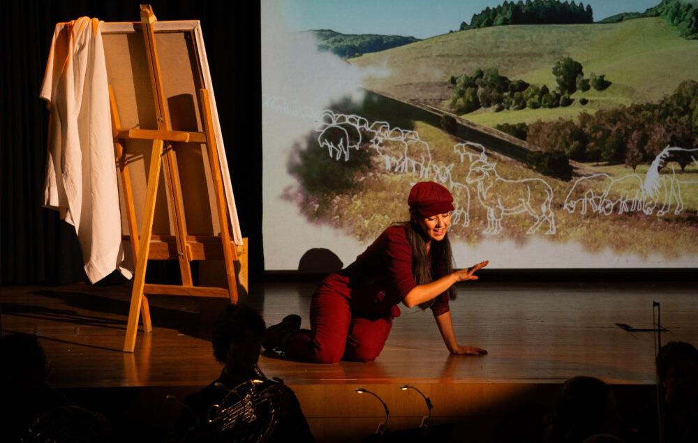 Representación operística en un escenario del distrito de Tetuán durante la celebración del Día Mundial de la Ópera, con intérprete frente a una proyección de paisaje rural y elementos escénicos que acercan la ópera al público.