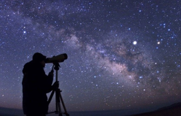 Persona con un telescopio viendo el universo