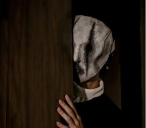 Persona con una máscara detrás de una puerta