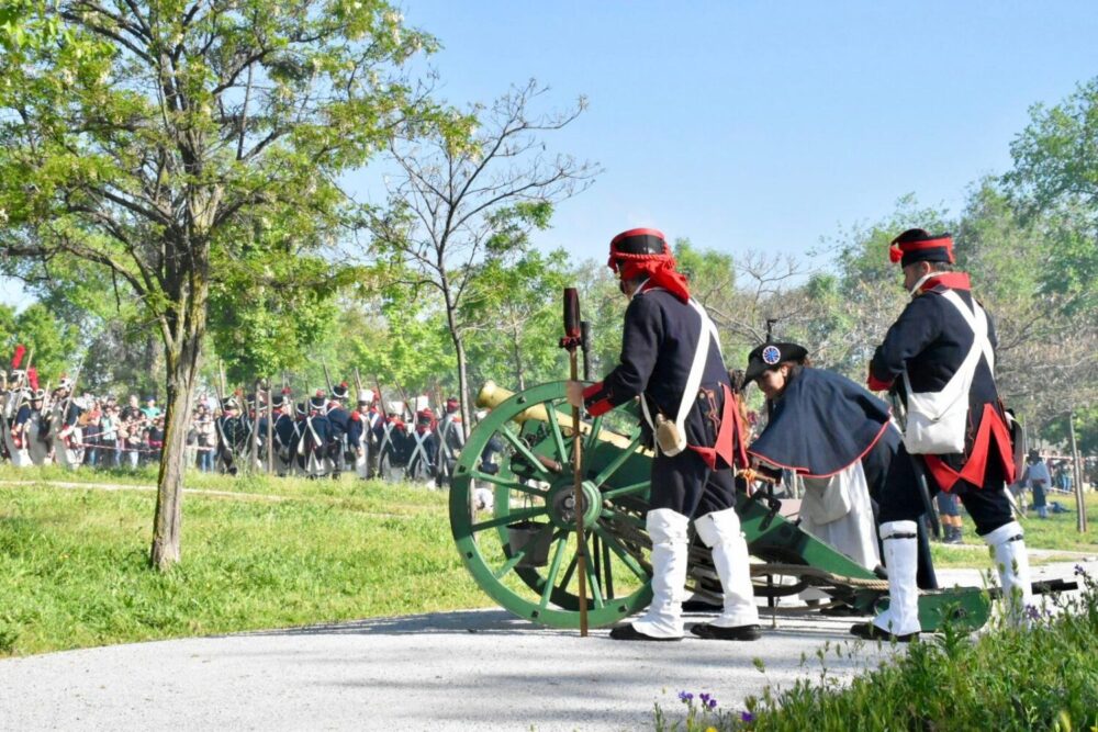 Actores vestidas de la época de Napoleón junto a un cañón de la época