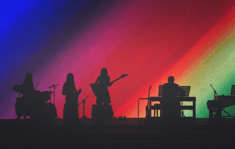 Siluetas de unos músicos con un fondo de colores azul, rojo, verde