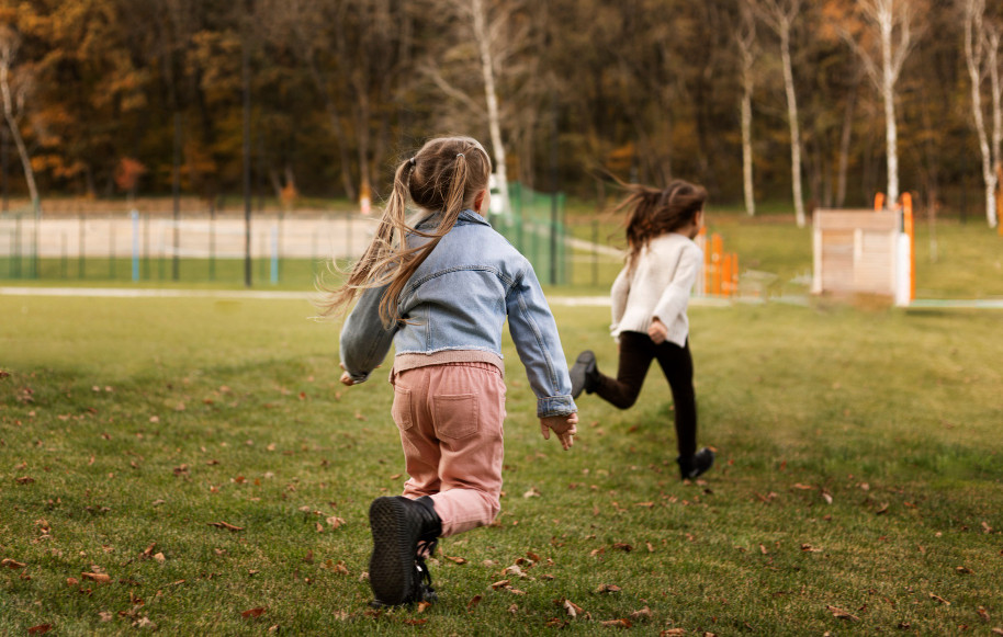 dos niñas corriendo en un campo con ropa de invierno