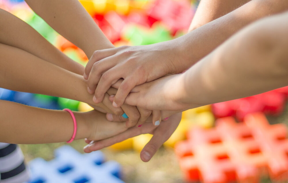 manos de niños juntándose en apoyo