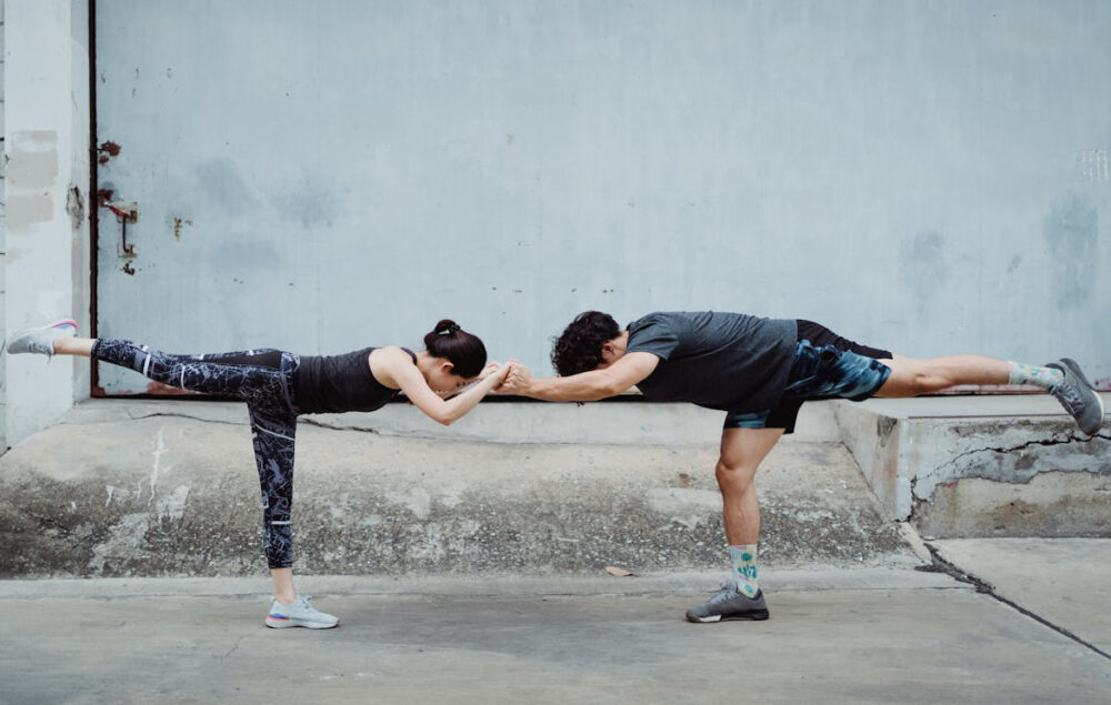 Una pareja haciendo estiramientos frente a una pared en la calle