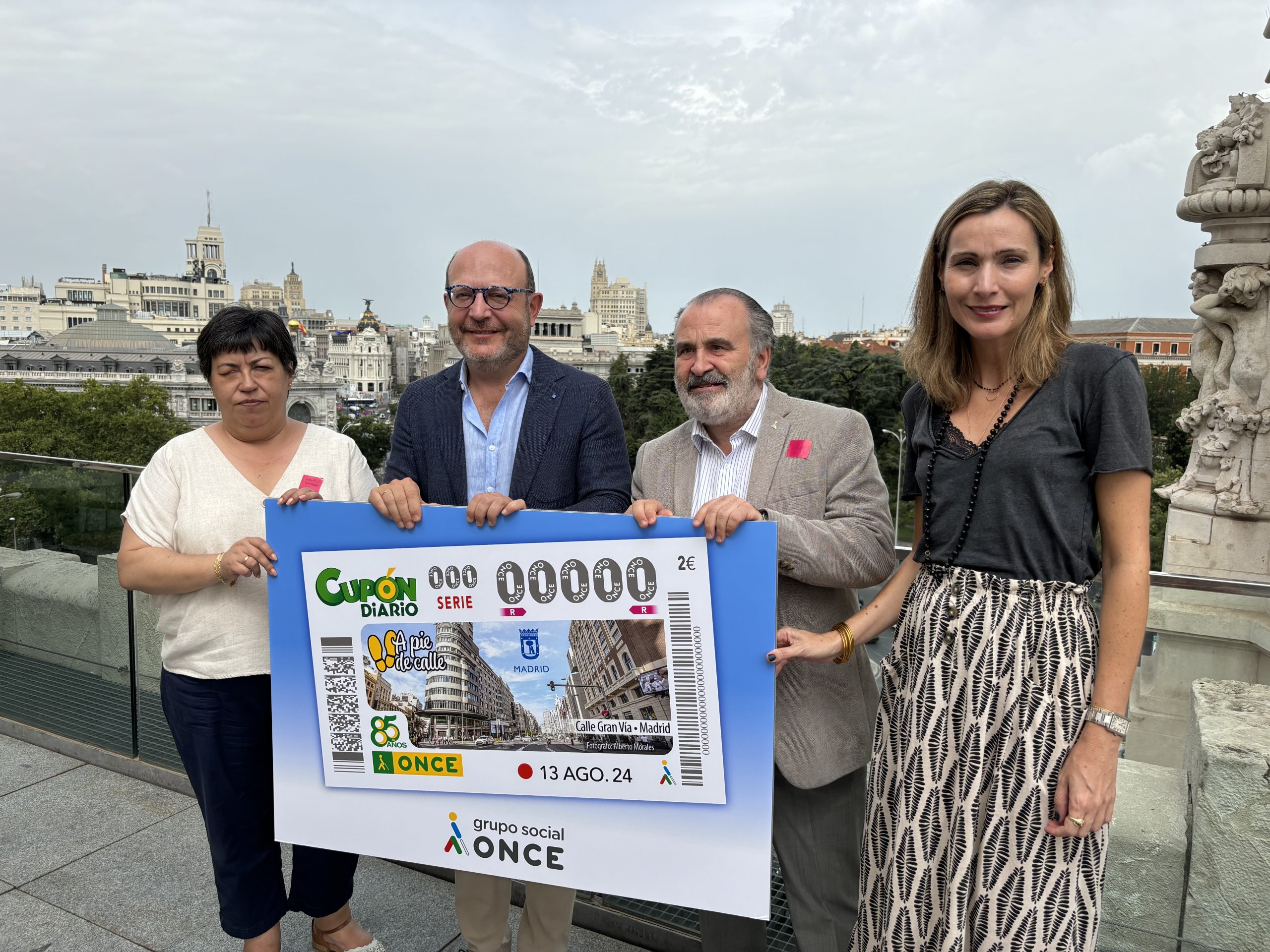 Cuatro personas sujetando un cartel donde se muestra un ejemplo de un cupón de la ONCE