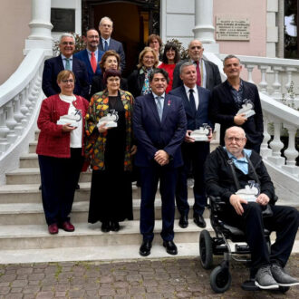 iMAGEN DE LOS galardonados en los II premios cultura en una escalera con un edificio señorial detrás