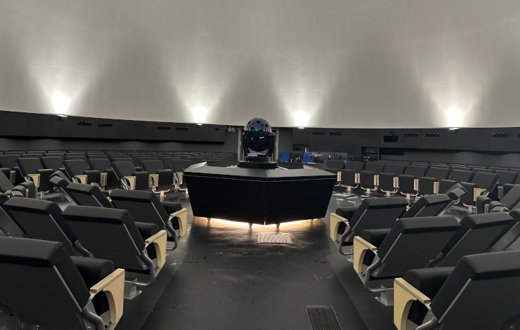 una sala con butacas y en el centro un proyector digital, una de las curiosidades del Planetario de Madrid
