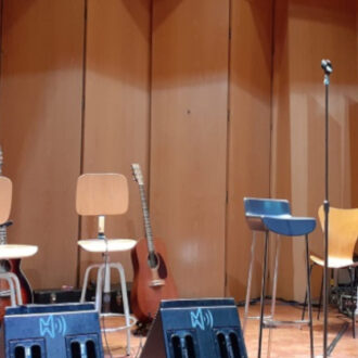 Imagen del escenario de Los Acústicos del Buenavista en el auditorio del Museo Lázaro Galdiano donde se ven los instrumentos y los roll ups corporativos