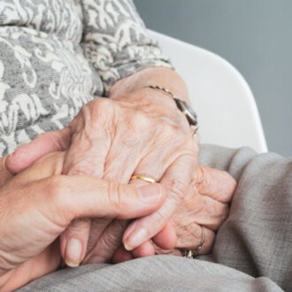 Plano donde se ve las manos de una persona mayor junto con las de una persona más joven